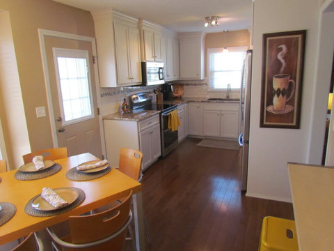 View of kitchen with off white kitchen cabinets and stainless steel appliances and door to large fenced in back yard.