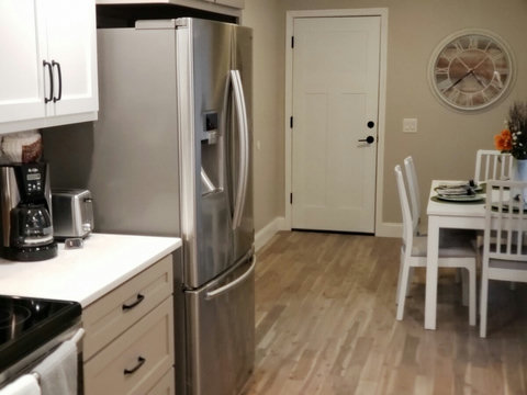Closer view of counter depth fridge and partial view of dining area along with the entrance from the garage.