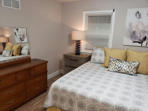 View of king bed, large night stand and mid century dresser..