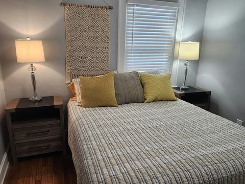 Front queen bedroom with nice lamps, faux window blinds and nightstands that have plugins.