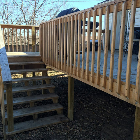 Stairs going up to large deck from back yard.
