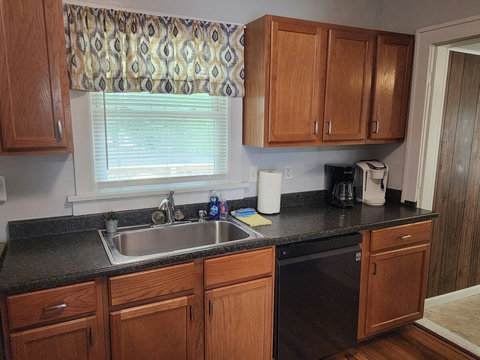 Another picture of kitchen sink and counter and door leading to laundry room that has door to deck and backyard.