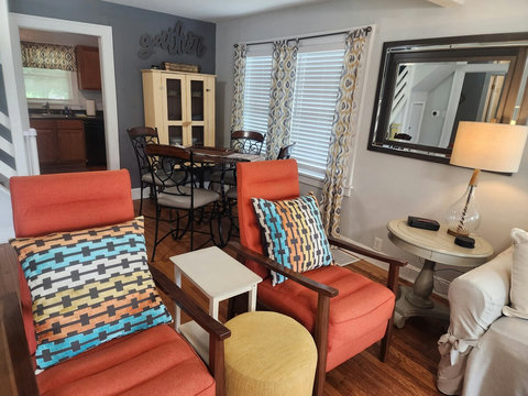 Retro custom orange recliners with dining counter height round table and chairs. More window to let in light if you light and view of entrance into kitchen area.