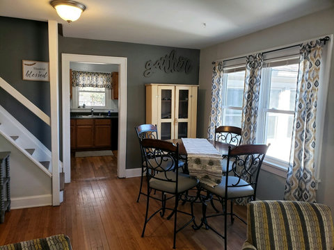 Counter height dining table and chairs. More windows and entrance to kitchen and stairs leading up the large loft/office area.
Also above the yellow cupboard is a cute sign that says gather.