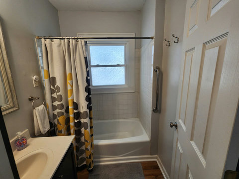 Picture of tub with grab bar on the side and hooks for hanging towels and sink