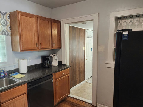View of right side of kitchen with the two coffee pots, built in shelf with wine glasses behind refrigerator and entrance to laundry room and back deck.