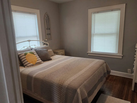 Back queen bedroom with white metal bed frame, two night stands and ikea night lights for reading, etc