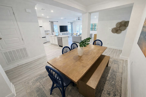 Coastal dining table opening to bright kitchen
