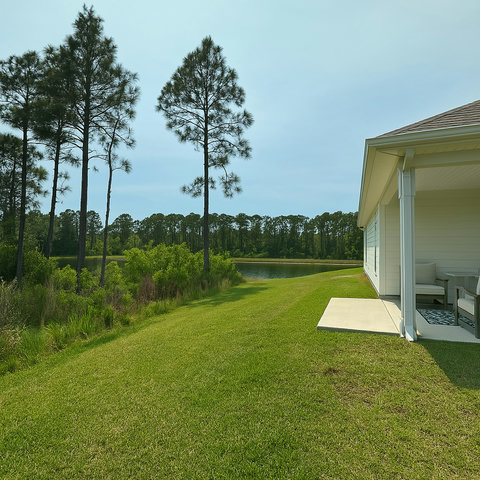 Patio overlooking lawn and tree-lined lake