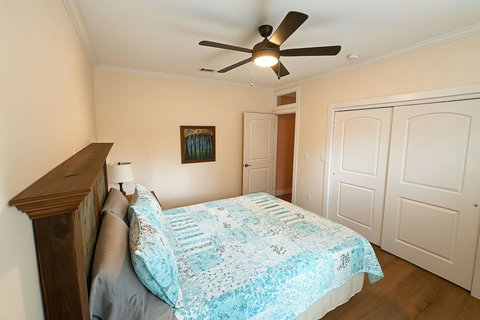 Coastal bedroom with blue quilt and closet space