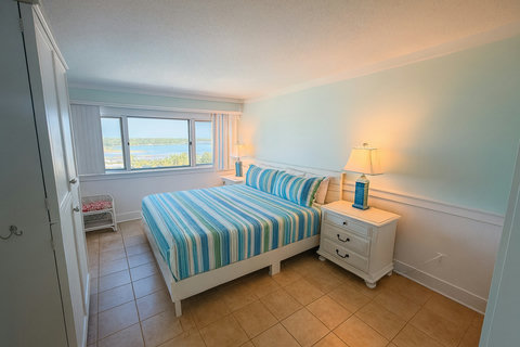 Bright bedroom with striped bedding and water views