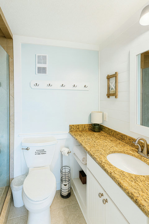 Bright bath with granite vanity and towel hooks
