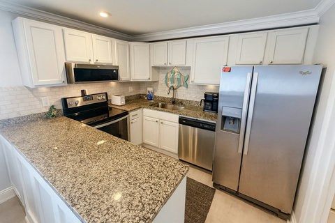 Stainless kitchen with granite peninsula and beach sign