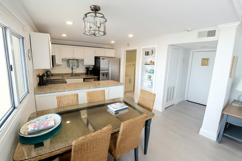 Glass dining table beside open granite kitchen bar