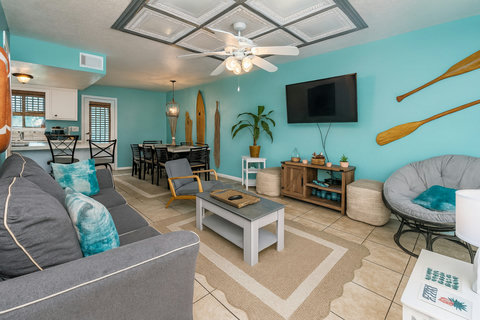 Turquoise living room with surfboards and oars on wall