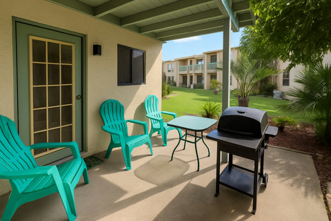 Ground patio with teal Adirondacks and charcoal grill