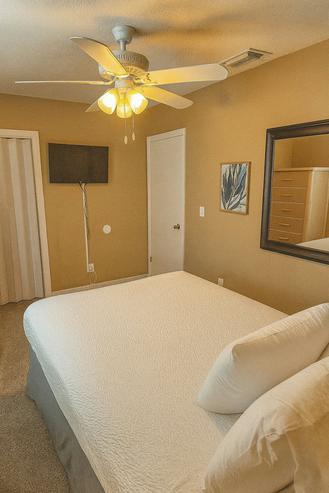 Cozy bedroom with wall-mounted TV and ceiling fan
