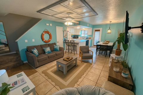 Open living, dining, and kitchen under coastal teal walls