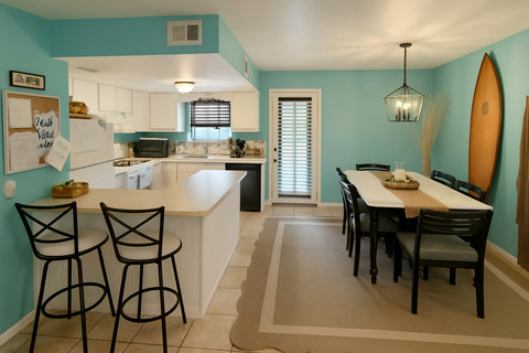 Open kitchen and dining with teal walls and surfboard