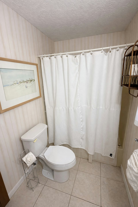 Clean bath with coastal art and shower tub