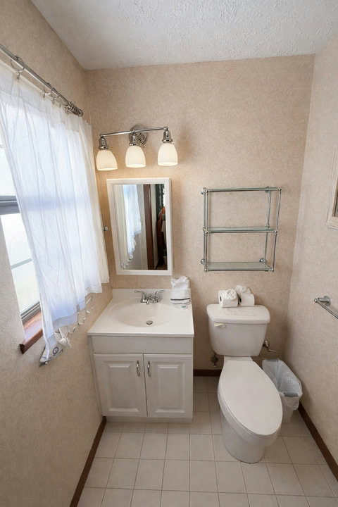 Guest bath with vanity sink and glass storage shelves