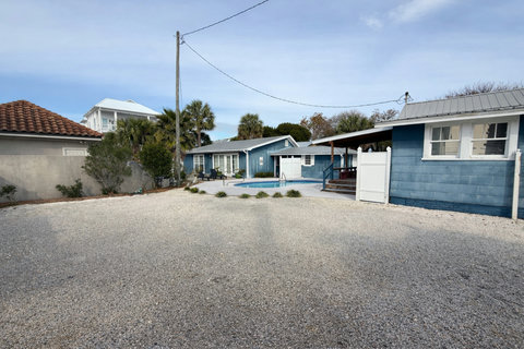 Blue cottage pool and gravel yard under clear skies