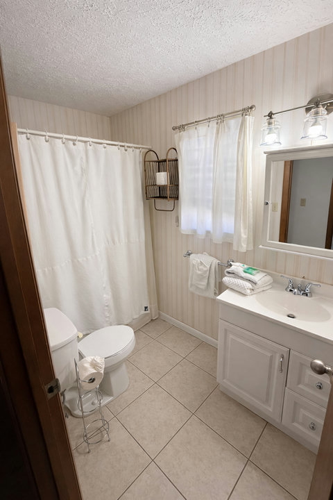 Bright full bath with vanity, tub, and fresh towels