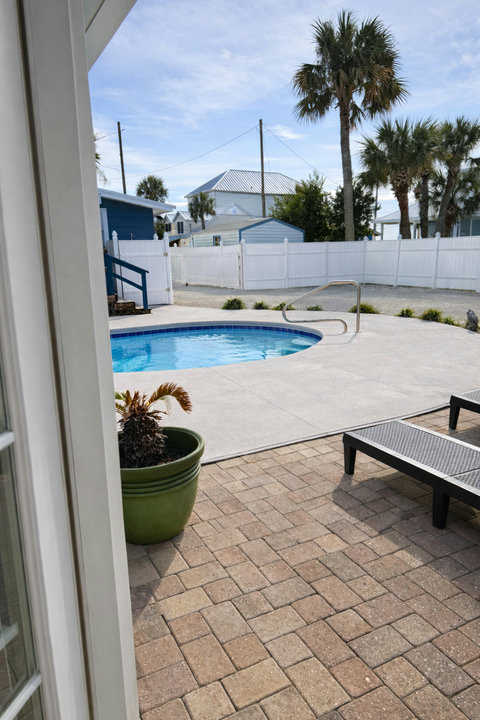 Sunlit pool with privacy fence and lounge chairs