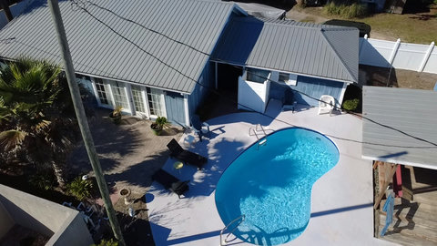 Private pool deck with loungers and blue cottage