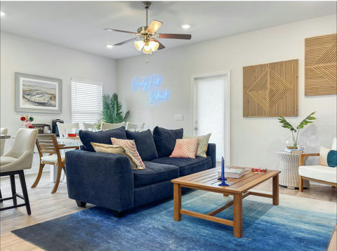 Navy sofa under glowing Sandy Feet Retreat neon