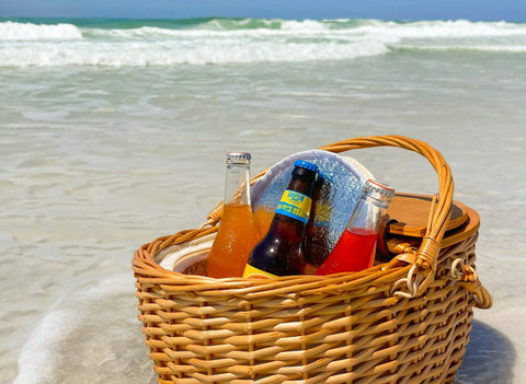 Wicker picnic basket with drinks by turquoise water