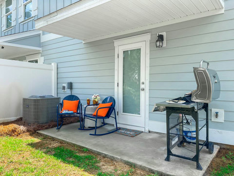 Private patio with rockers, orange pillows, and grill