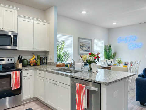 White kitchen island opening to neon-lit dining