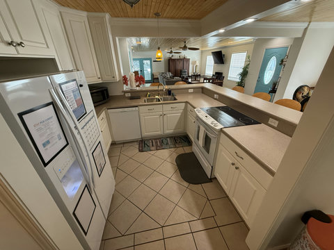 Open white kitchen overlooking wood-ceiling living room