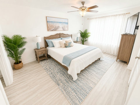 Spacious coastal bedroom with dresser and TV