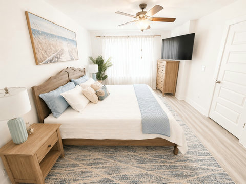 Coastal bedroom with blue accents and wall-mounted TV
