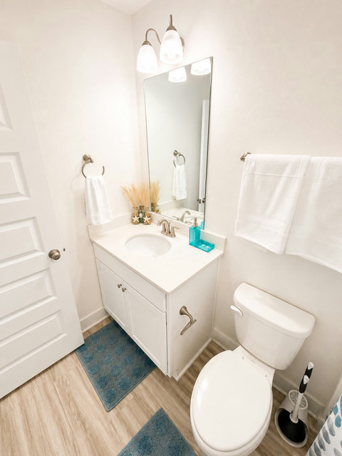 Bright bathroom with white vanity and blue mats