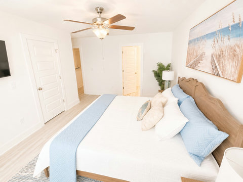 Serene bedroom with scalloped headboard and beach art
