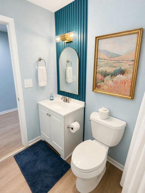 Bathroom with teal slat wall and gold arched mirror