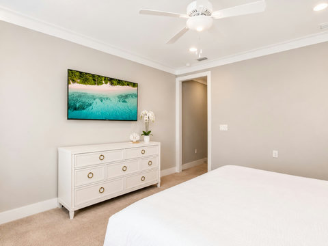 Bedroom – Restful bedroom with a coastal-mural TV above a wood dresser and a comfortable bed.