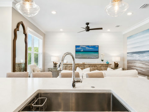Kitchen – Island prep space with a deep stainless sink overlooking the open living room and coastal artwork.