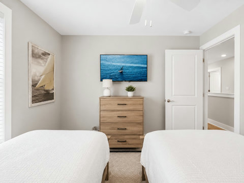 Bedroom – Guest bedroom with two beds, a wood dresser, and a coastal sailfish TV display.