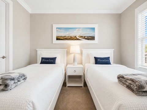 Bedroom – Bright bedroom with two twin beds, coastal artwork, and plush bedding.
