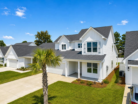 Exterior – Front street view of the home showing its bright coastal exterior, mature palm, and manicured landscaping.