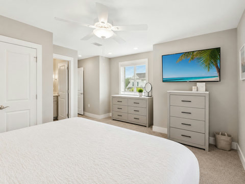 Primary Bedroom – Spacious primary suite with a mounted TV, dresser, and calming neutral palette.