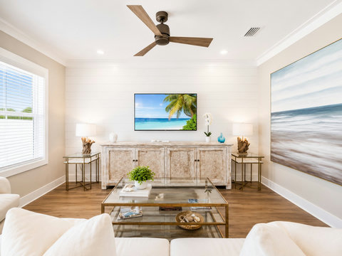 Living Room – Airy lounge featuring a mounted TV above a coastal media console and an oversized beach mural.