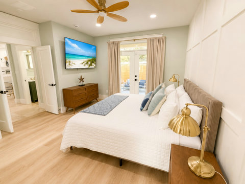 Retreat to the serene primary suite with a plush bed, coastal decor, and a smart TV.