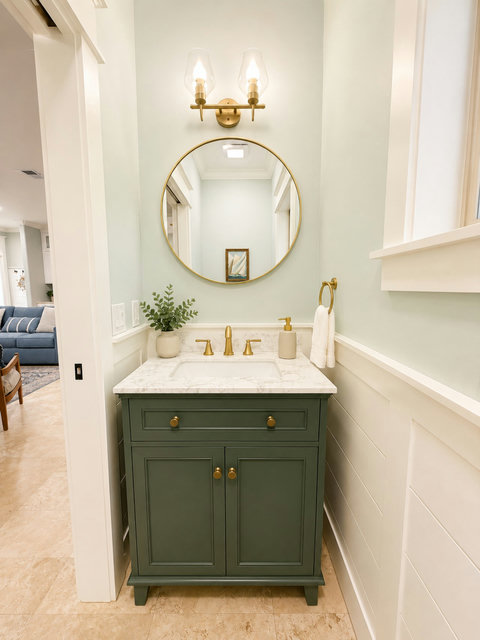 A charming powder room with a bold green vanity and gold accents for guests.