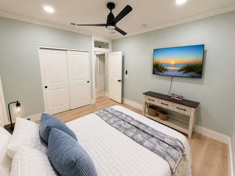 A bright bedroom with a smart TV and ceiling fan for lazy mornings.