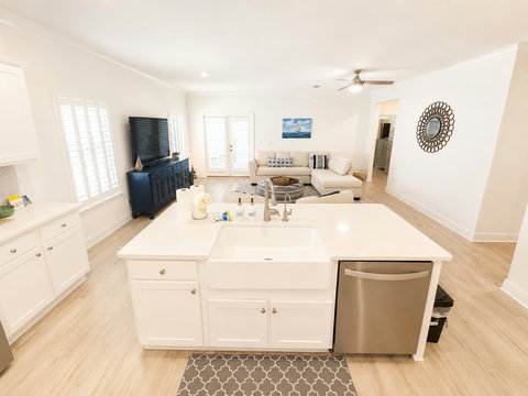 A bright island kitchen with a farmhouse sink flows into the living room—the perfect open layout for cooking and gathering together.